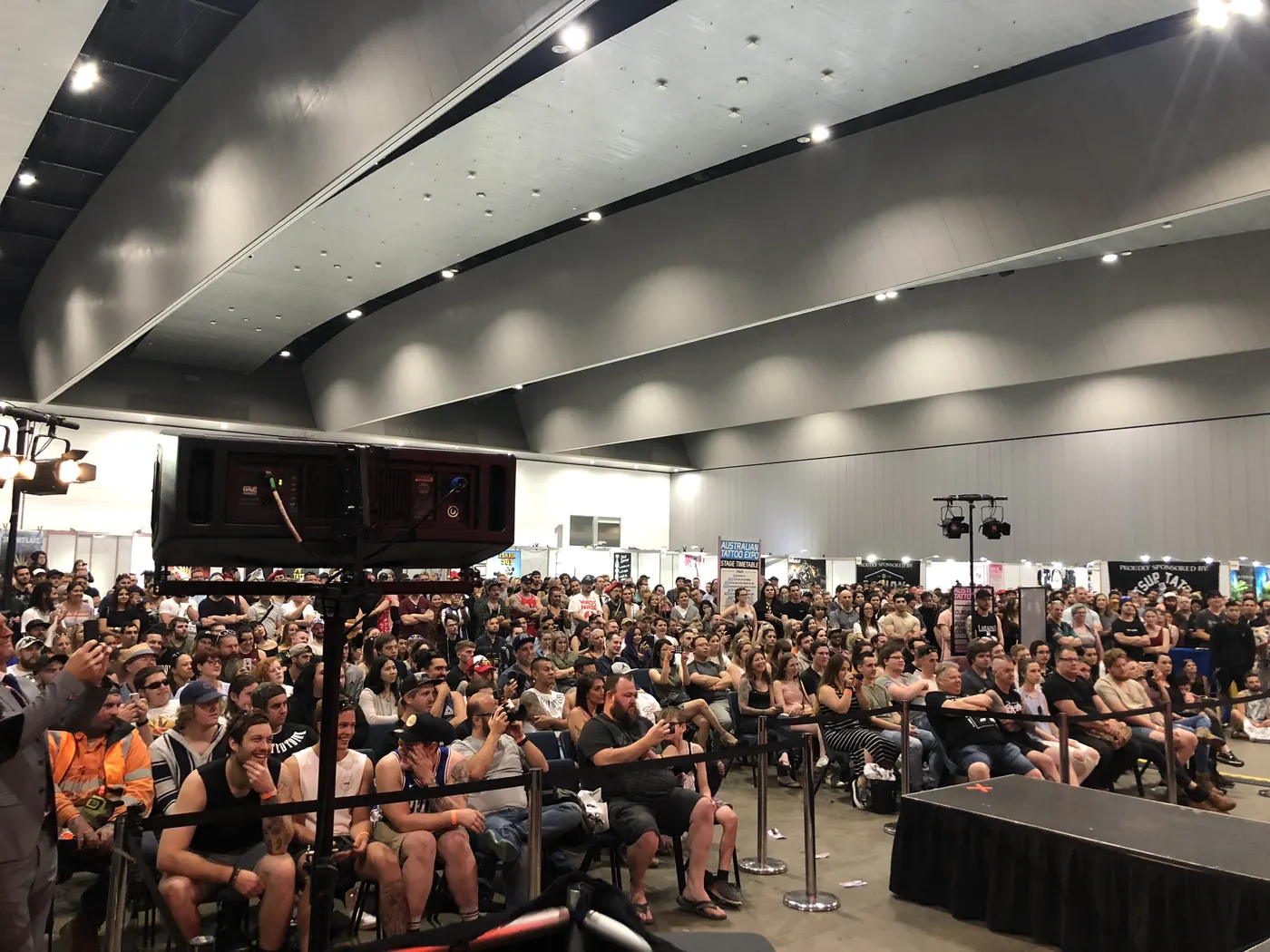 A seated audience filling a hall in front of a stage